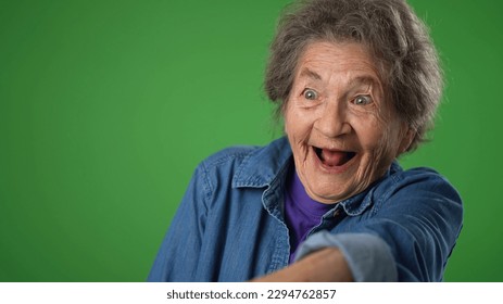 Closeup funny crazy portrait of happy elderly senior old woman with wrinkled skin and grey hair smiling and look around for friend find meet greet someone posing on green screen background. - Powered by Shutterstock