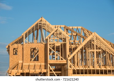 Close-up Of Gables Roof On Stick Built Home Under Construction And Blue Sky In Humble, Texas, USA. New Build Roof With Wooden Truss, Post And Beam Framework. Timber Frame House, Real Estate Background