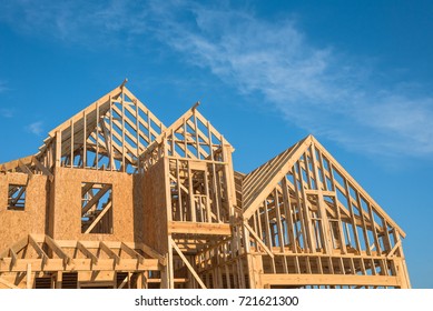 Close-up Of Gables Roof On Stick Built Home Under Construction And Blue Sky In Humble, Texas, USA. New Build Roof With Wooden Truss, Post And Beam Framework. Timber Frame House, Real Estate Background