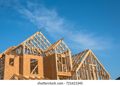 Close-up Of Gables Roof On Stick Built Home Under Construction And Blue Sky In Humble, Texas, USA. New Build Roof With Wooden Truss, Post And Beam Framework. Timber Frame House, Real Estate Background