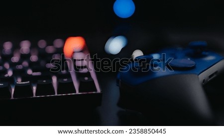 A close-up of a gaming setup, consisting of a controller and a keyboard on a desk