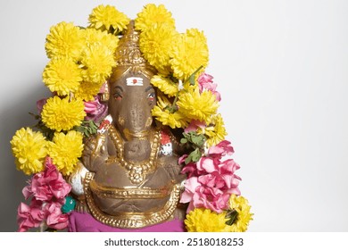 Close-up of Ganesha statue decorated with flower garlands on white background on Ganesha Chaturthi celebration. - Powered by Shutterstock