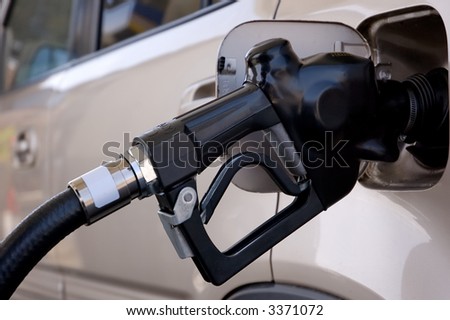 Closeup of a gasoline pump nozzle in the tank of an SUV