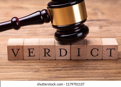 Close-up Of A Gavel Over Wooden Blocks With Text Verdict On Table