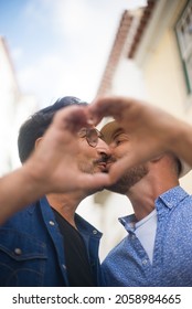 Close-up Of Gay Men Kissing. Mid Adult Man In Casual Clothes Showing Affection, Making Heart Sign With Hands. Love, Affection, Relationship Concept