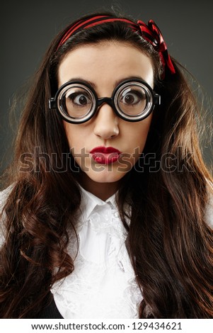 Closeup of geeky young schoolgirl with funny glasses, over gray background