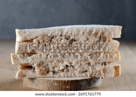 Close-up of a generously filled chicken and stuffing sandwich stack, cut in half, resting on a rustic wooden coaster, ready for a delicious lunch