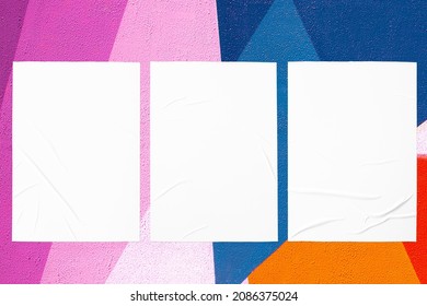 Closeup Of Geometrical Blue Orange Purple Pink Painted Urban Wall Texture With Three Wrinkled Glued Poster Templates. Modern Mockup For Design Presentation. Creative Geometric Urban City Background. 