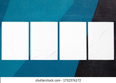 Closeup of geometrical colorful painted urban wall texture with four wrinkled glued poster templates. Modern mockup for design presentation with clipping path. Creative urban city background. 