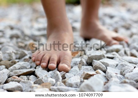 Closeup of a girl bare feet walking on stones rock