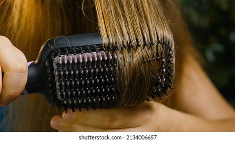 Close-up Of A Girl Brushing And Drying Her Hair With An Electric Hair Straightener. Heated, Ceramic, Non-damaging Hair Brush. Hair Care