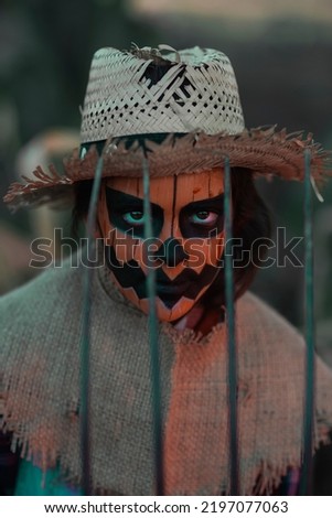 Close-up of a girl dressed as a Halloween pumpkin, with a pitchfork in front of her face