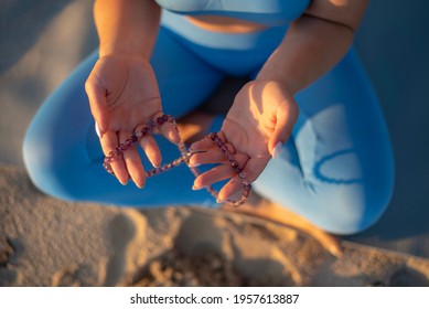 close-up girl on the beach. young woman holds a rosary for meditation in her hands. focus on hands - Shutterstock ID 1957613887