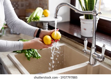 Close-up of a girl s hands washing a lemon in the sink in a home kitchen. The concept of health and a healthy lifestyle. Healthy eating, diet, vegetarianism