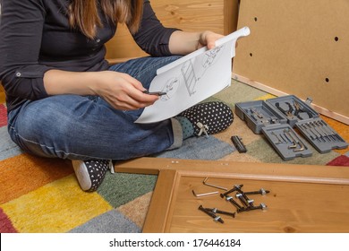 Closeup of girl with tools reading the instructions to assemble a new furniture for home