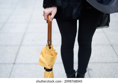 Close-up Of A Girl's Hand Holding A Yellow Closed Umbrella.