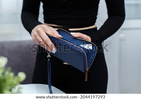 Close-up of a girl's hands with an open purse in her hands. An empty wallet is a woman with no money in her wallet. Wallet made of genuine blue leather