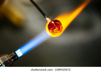 Close-up of glass bead melting in gas-burner fire, craftwork