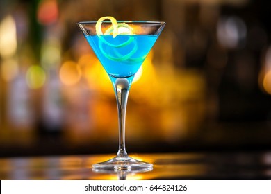 Closeup glass of blue lagoon cocktail decorated with lime at festive bar counter background.