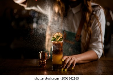 Close-up of glass with bumble coffee cocktail on the table and female bartender carefully sprinkles on it - Powered by Shutterstock