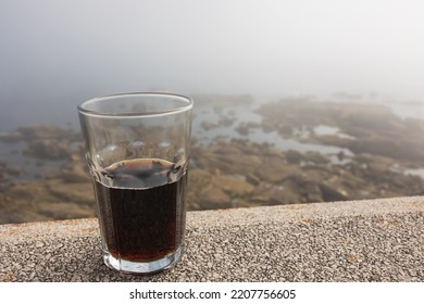 Close-up Glass Glass With Coke On The Stone Ocean Shore In Foggy Weather.