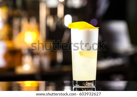 Closeup glass of gin fizz cocktail with lemon and whip eggwhite at bar cpunter background.