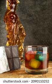 close-up glass glass high alcohol whiskey with colored ice blocks and bottle body carafe drink concept