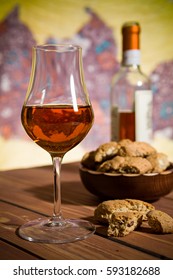 Closeup of a glass of Italian vin santo wine and cantucci biscuits on a wooden table
