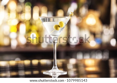 Closeup glass of martini dry cocktail with olives at bar counter background.
