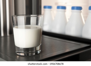 Un verre de lait en gros plan sur la porte du frigo avec un groupe de bouteilles de lait en plastique stockées et alignées en arrière-plan. Le calcium est bon pour la santé