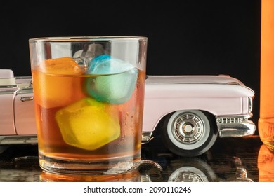 close-up glass glass of spirit whiskey with colored ice blocks and bottle classic car drink concept