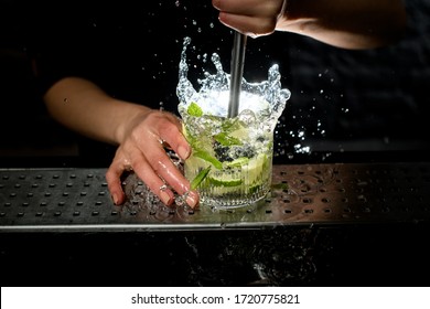 close-up of glass with splashing caipirinha cocktail with pieces of ice, lime and mint leaves. - Powered by Shutterstock