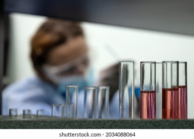 Closeup Of Glass Tubes At The Laboratory And Woman Scientist Silhouette On The Background