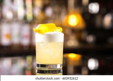 Closeup Glass Of Whiskey Sour Cocktail Decorated With Lemon At Bar Background.