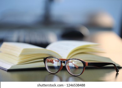 Close-up of glasses on table in library open book is the background selective focus and shallow depth of field