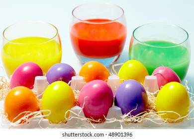 Close-up of glasses with painted water and Easter eggs near by