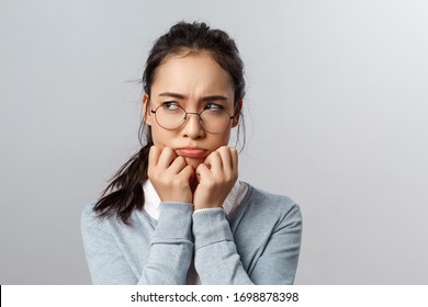 Close-up of gloomy offended young silly asian woman, sulking frowning upset, look left with envy or regret, have hard feelings, insulted of unfair situation happened her, stand grey background