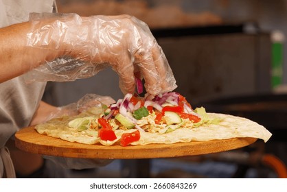 Close-up of vendor’s gloved hands assembling a fresh vegetable wrap at a farmers market in Prague, Czech Republic.