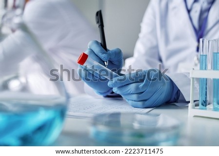 Close-up of gloved hands of clinician with pen writing down sample name