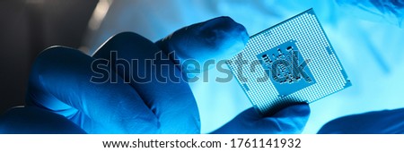 Close-up gloved hands holding detail microchip. Man in special uniform shows microprocessor chip. Production technology hitech. Repair microprocessor electronics electrical equipment.