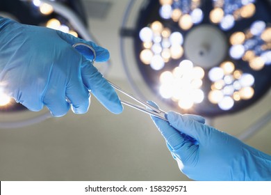 Close-up of gloved hands holding surgical scissors - Powered by Shutterstock