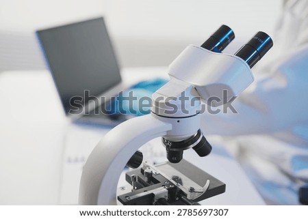 A close-up of a researcher’s gloved hands typing on a laptop keyboard next to a notebook and lab equipment, symbolizing the transition from physical experimentation to digital data analysis.