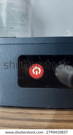 Close-up of a glowing red power button on an electronic device. Featuring a clear power symbol, suitable for tech, hardware, office equipment, or electronics-related content