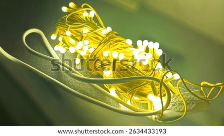 Closeup of glowing yellow LED string lights tangled on a surface, emitting a warm, festive glow. Perfect for holiday, celebration, or home décor themes emphasizing lighting and atmosphere.