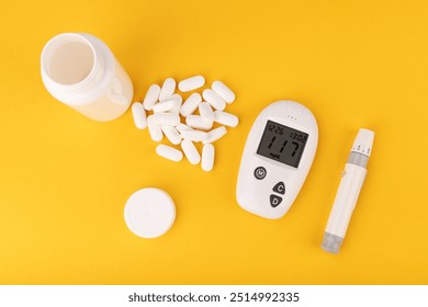 Close-up of a glucose meter, white pills, and a hand taking a pill against a yellow background. Perfect for illustrating diabetes care and medication - Powered by Shutterstock