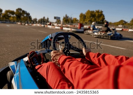 Closeup go-kart racer driving sportcar, focus on hands holding steering wheel