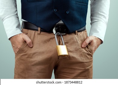 Close-up of a gold padlock hanging from a man's belt. The concept of marital fidelity, celibacy, treason, chastity belt
