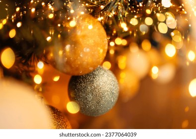 Close-up of gold and silver balls on the Christmas tree. Beautiful bokeh effect with lights. Sparkling Christmas garland. New year card or background.