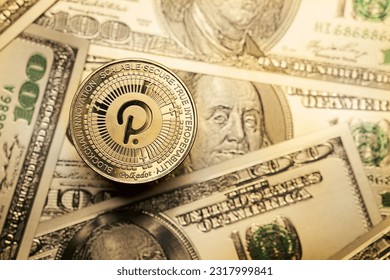 Close-up of golden Polkadot cryptocurrency on 100 dollar bills