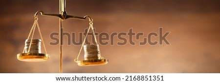 Close-up Of Golden Stacked Coins On Justice Scale